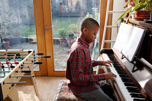 Boy playing at an upright piano with good posture and technique