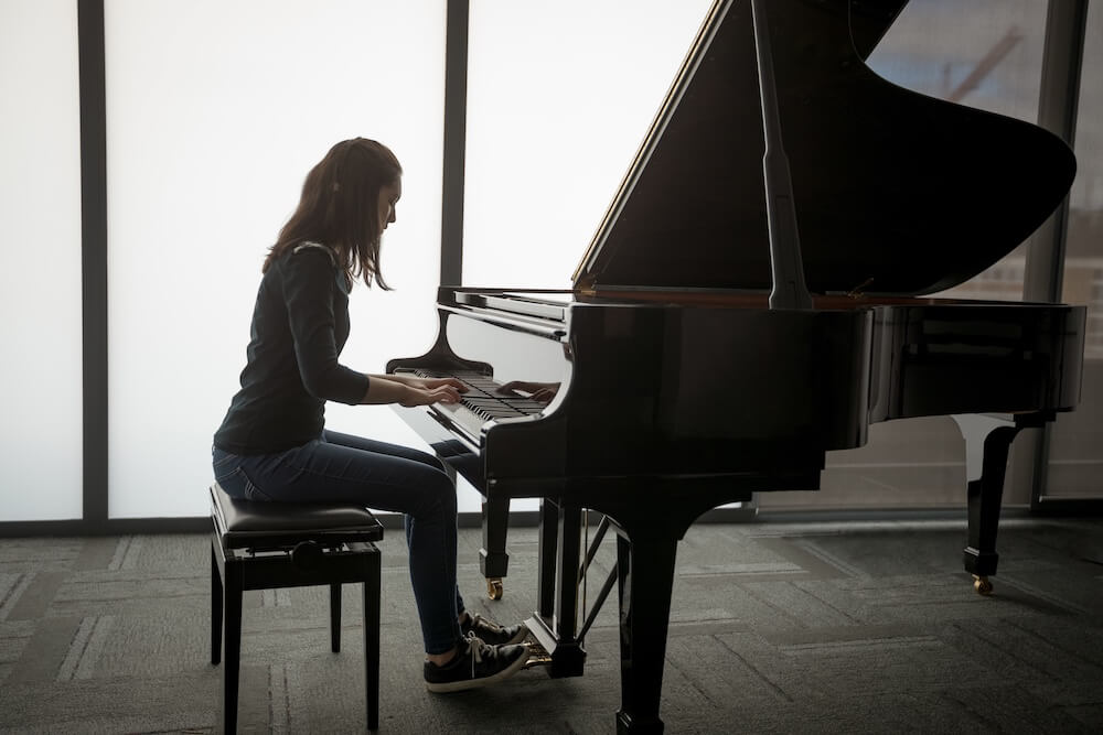 Teenage girl playing on a grand piano with good posture and technique